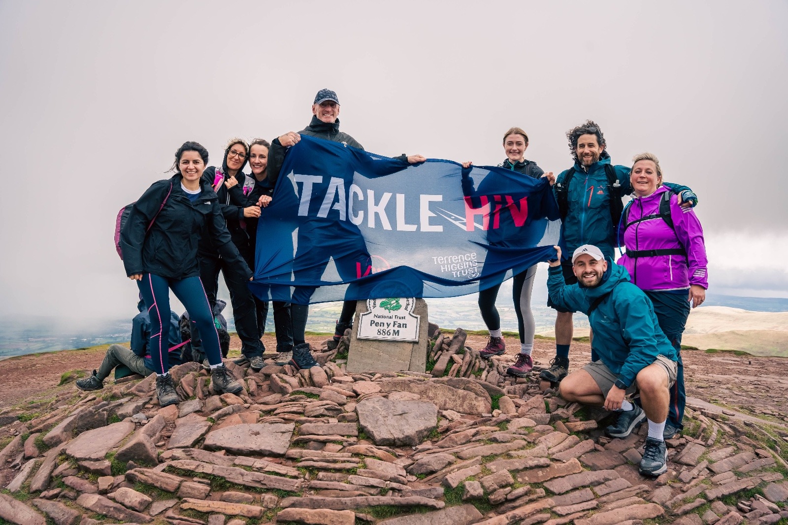 Gareth Thomas and other mountain climbers at the summit with a "Tackle HIV" banner.