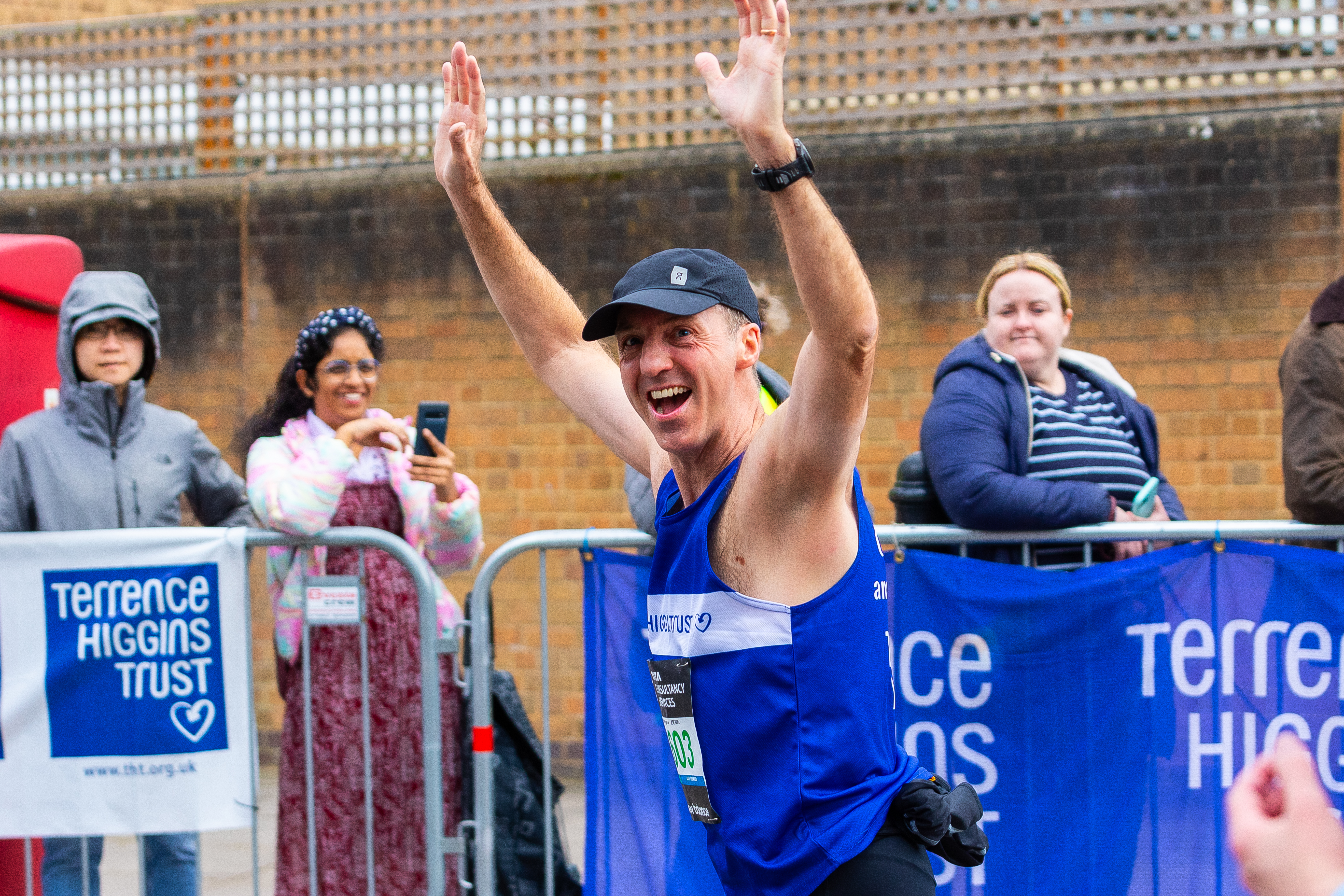 A smiling Terrence Higgins Trust London Marathon runner with his arms up.