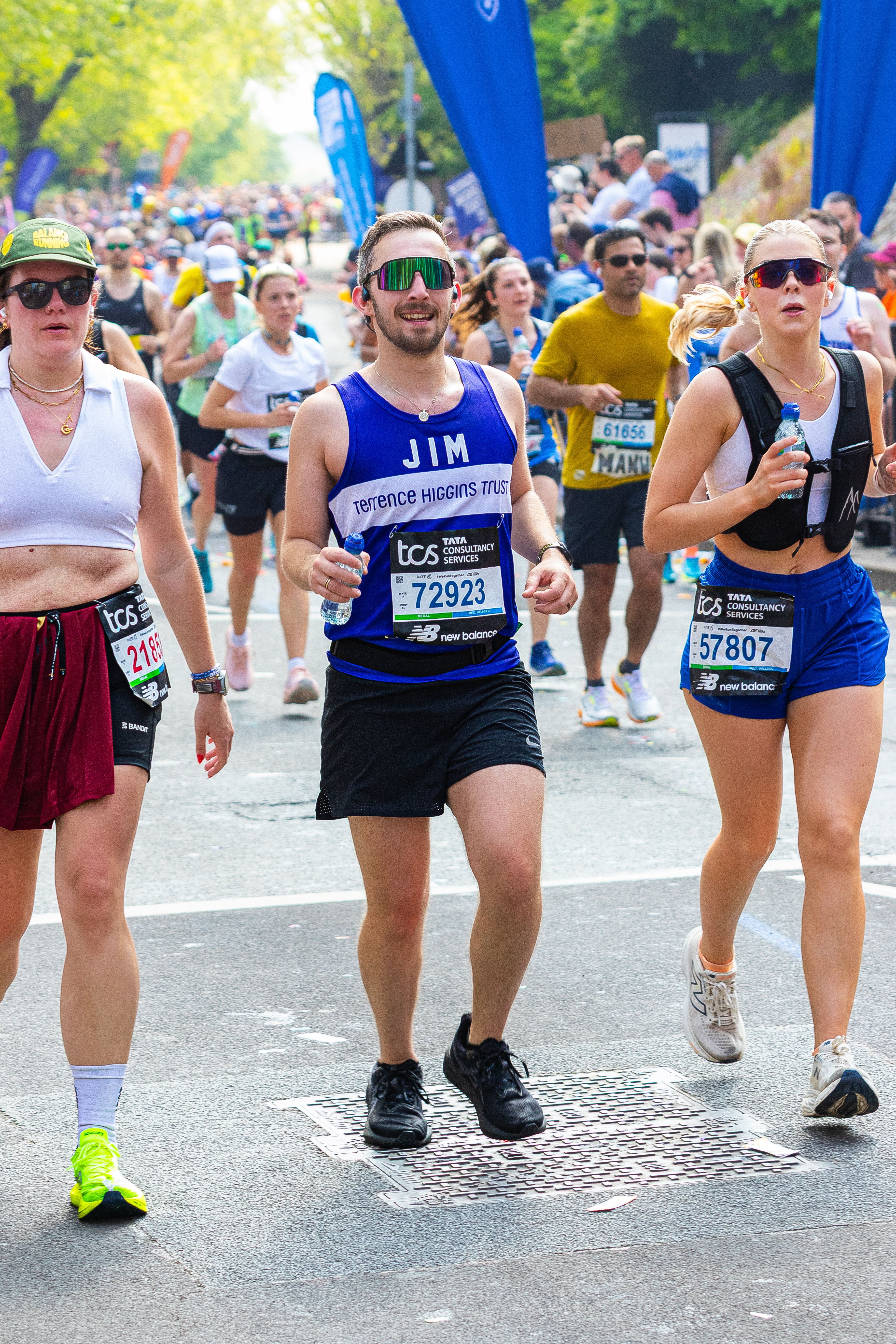 A Terrence Higgins Trust runner with sunglasses, holding a water bottle at the London Marathon.