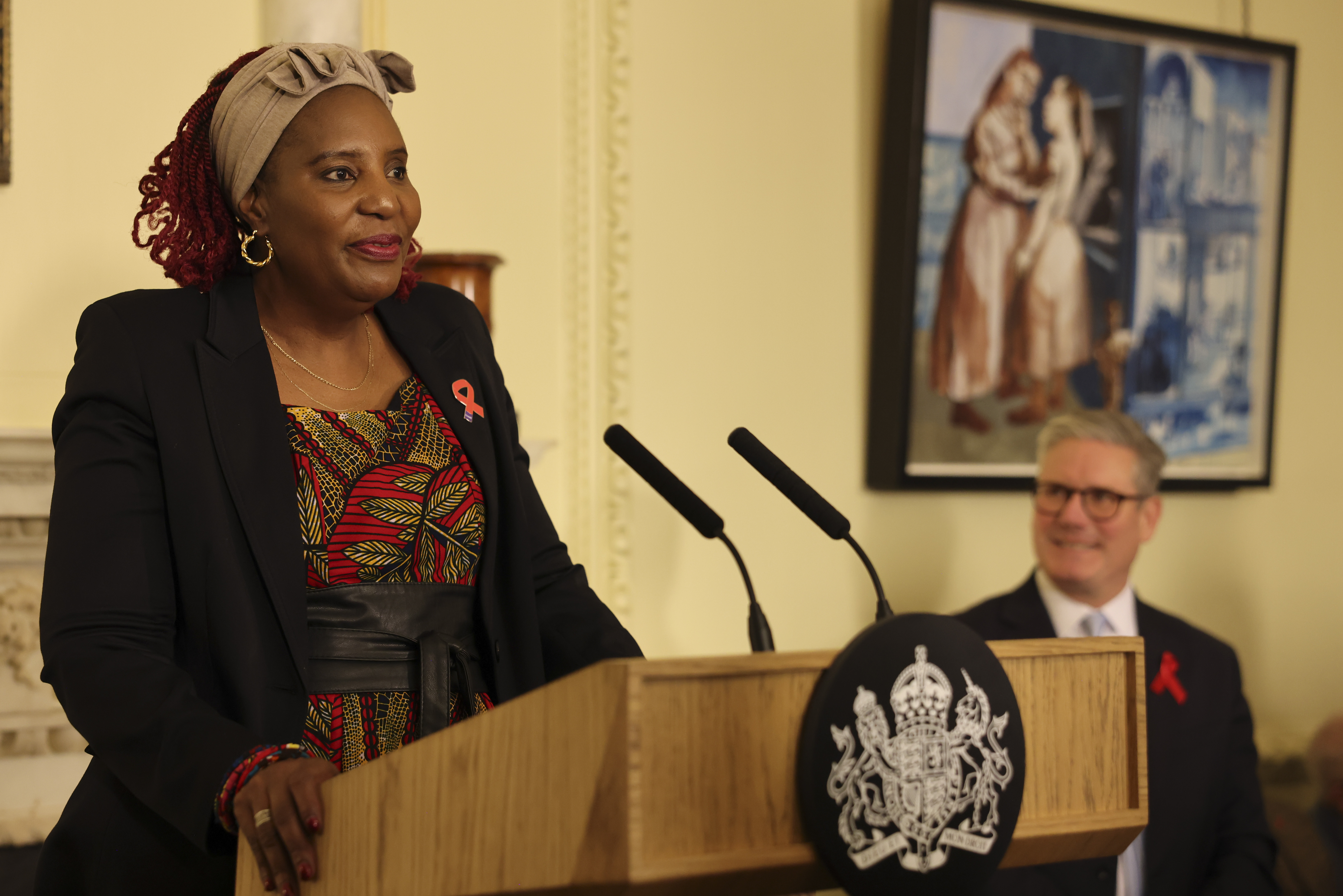 Memory Sachikonye delivering a speech with Keir Starmer in the background.