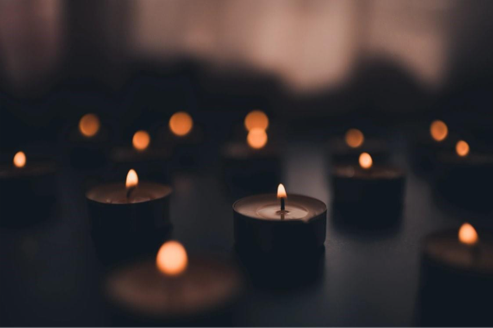 Lit tealight candles on a dark background.