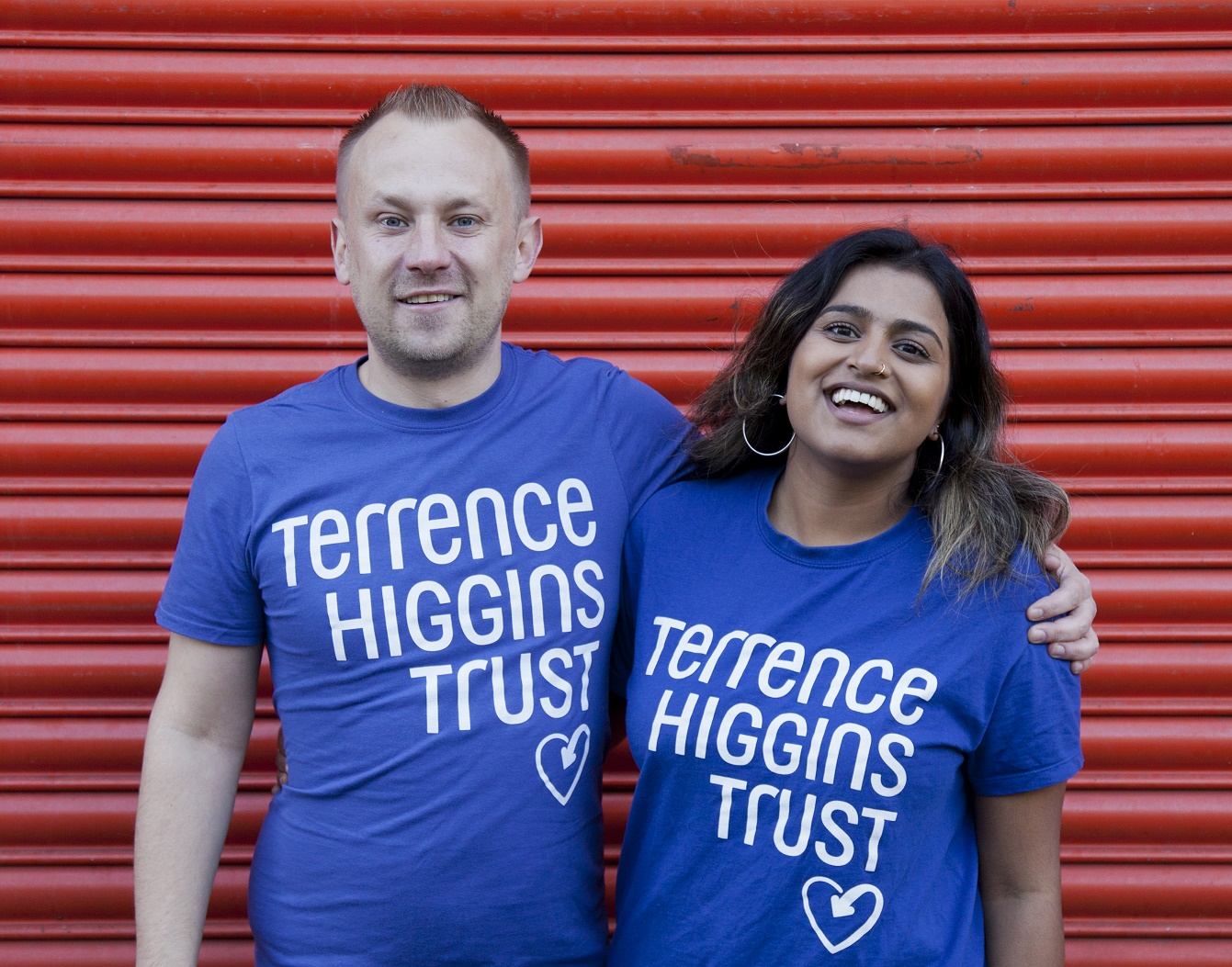 A man with his arm around a woman, both in Terrence Higgins Trust t-shirts.