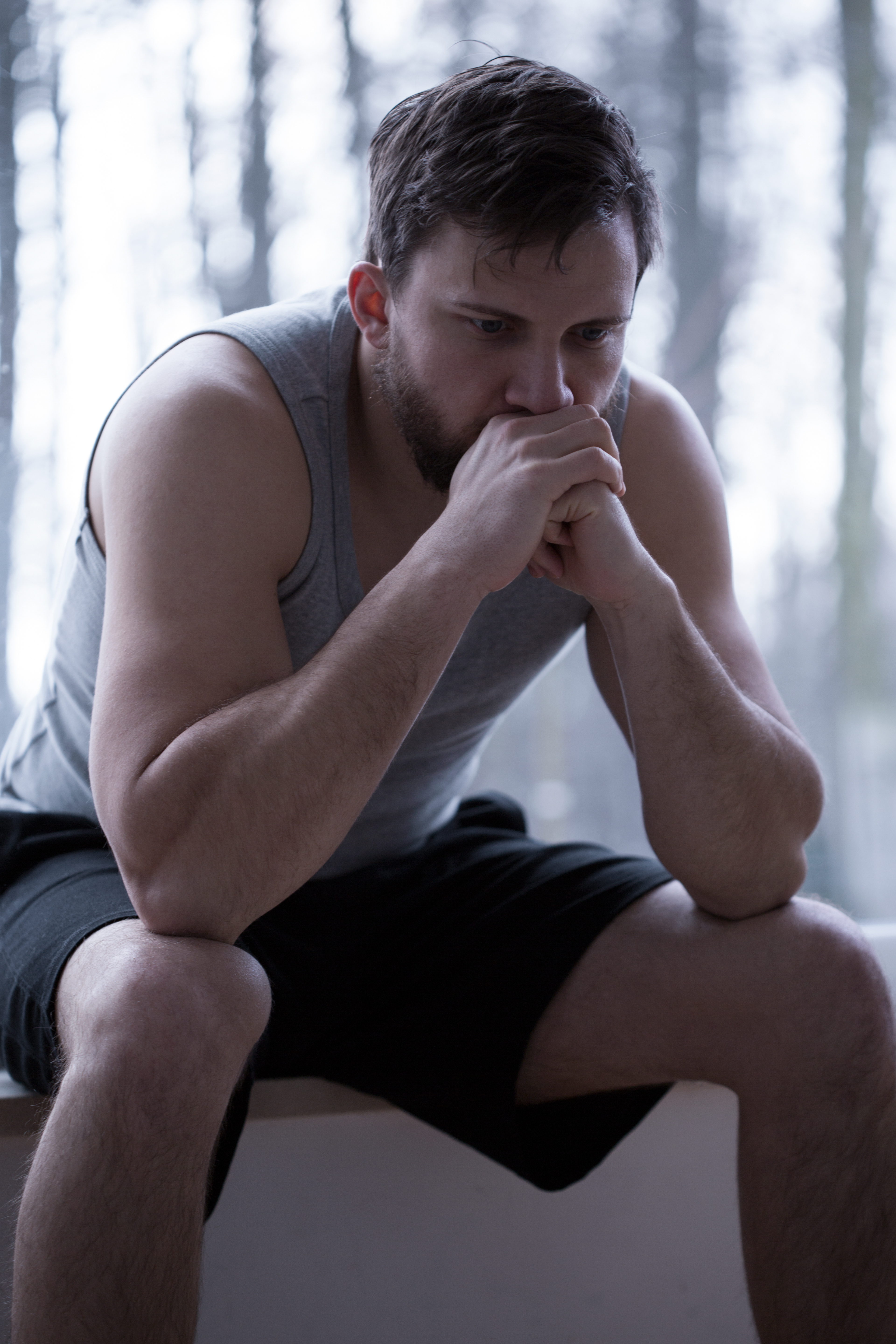 A man sitting with and hands towards his face with a sad facial expression.