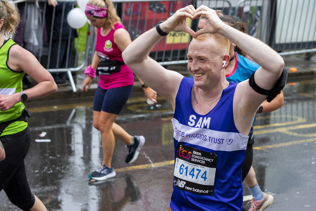 Runner in Terrence Higgins Trust gear forming a heart above his head with his hands.