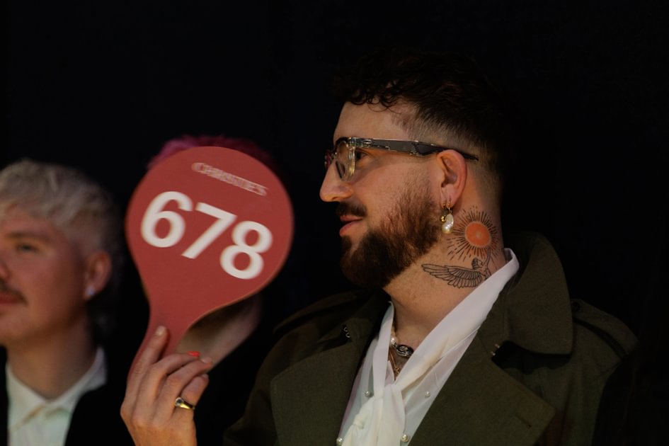 An attendee at the 2026 Terrence Higgins Trust auction holds up a bid paddle.