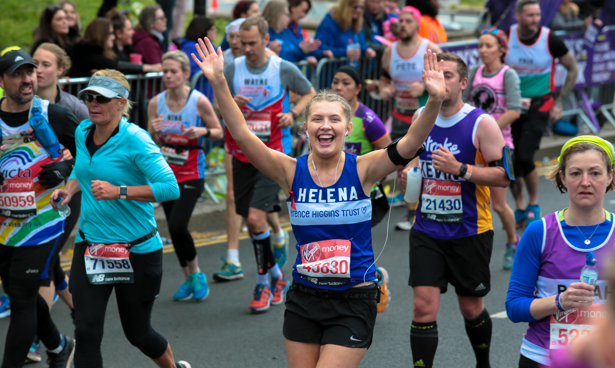 Helena running the London Marathon with arms up in celebration