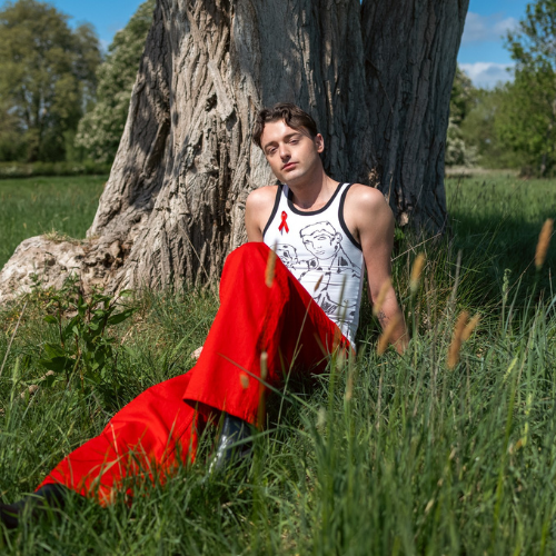 Adam from I Kissed a Bay sits on the grass underneath a tree.