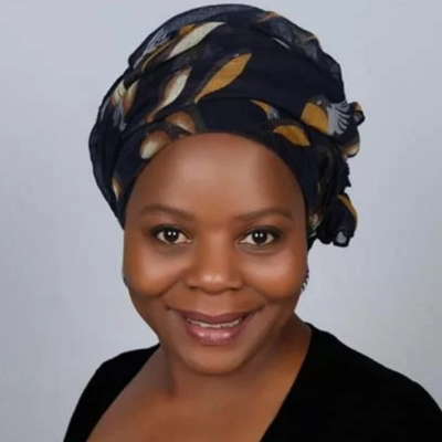 Photo of a woman smiling at the camera, with a grey background.