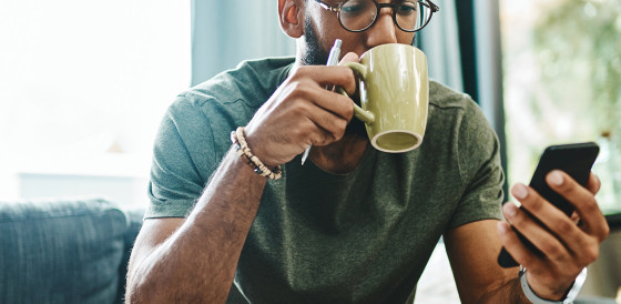 Man sipping tea looking at phone