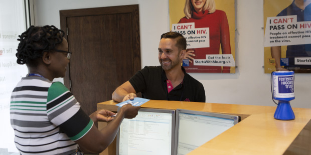 Man being given a leaflet in at a Terrence Higgins Trust reception desk