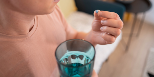 PrEP block Person holding a blue pill in their hand and a glass of water.