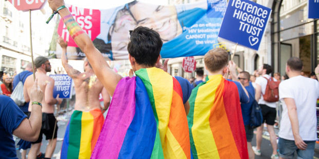 Pride marchers wearing rainbow cloaks