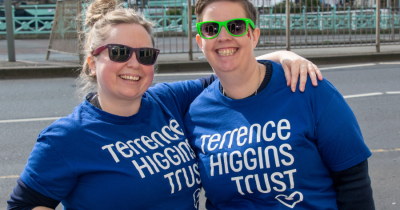 Two people in Terrence Higgins Trust t-shirts standing outside.