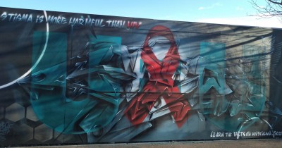 Wall mural in Dundee with red ribbon and message reading "stigma is more harmful than HIV"