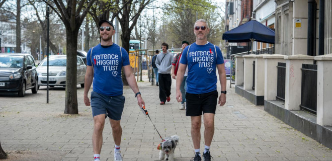 Two men in Terrence Higgins Trust t-shirts with a dog on a leash.