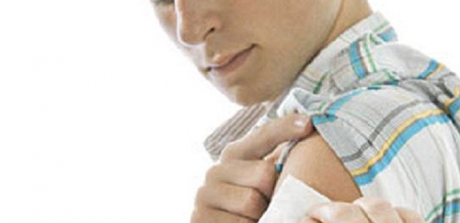 Man holding patch on arm after vaccination