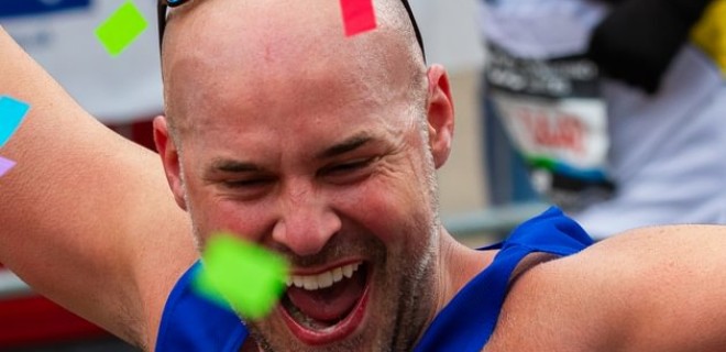 A Terrence Higgins Trust runner at the 2024 London Marathon with his arms up in celebration.