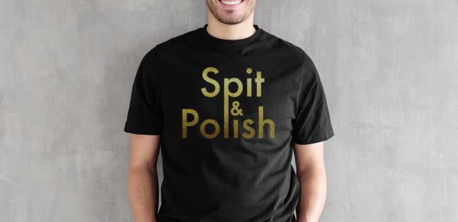 A model against a grey background wearing a black T-shirt with gold 'Spit & Polish' slogan.