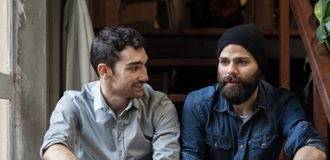 Two men sitting on a step in discussion.