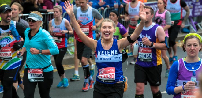 Helena running the London Marathon with arms up in celebration