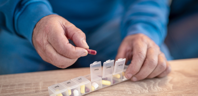 A older person uses a pill box