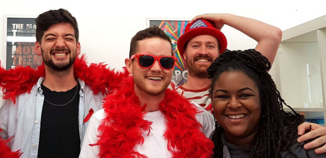 Four young people wearing red boas and hat