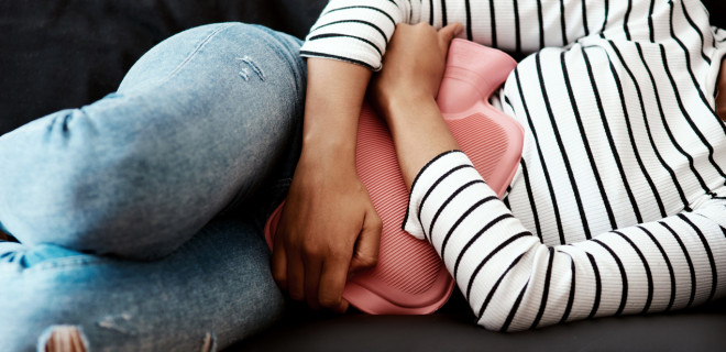 Holding hot water bottle to stomach