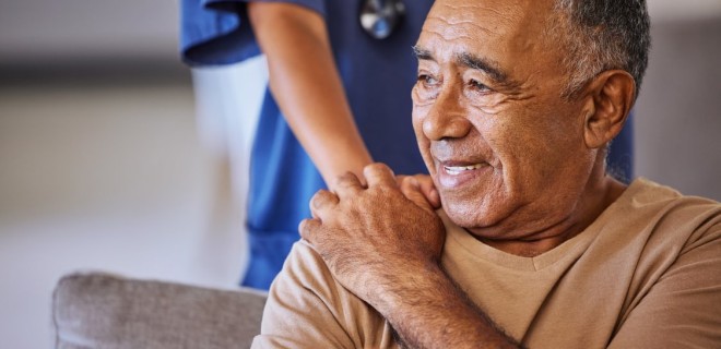 older man with a nurse's hand on his shoulder