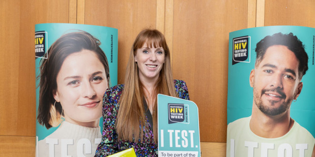 Angela Rayner MP in front of National HIV Testing Week posters, holding a test kit
