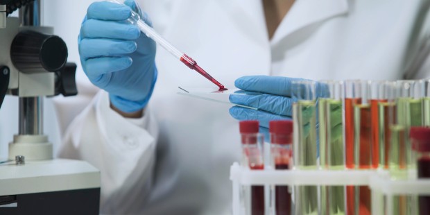 A laboratory technician handling a blood sample with a pipette. 