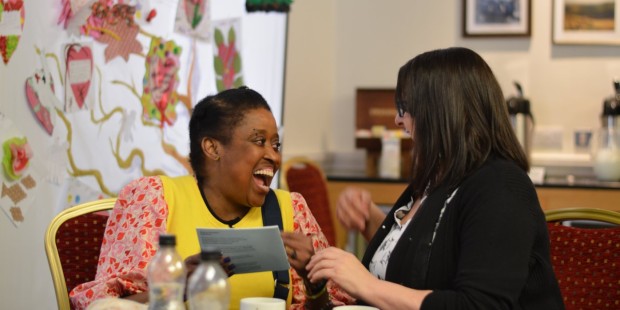 Two women talk and laugh together.