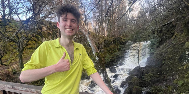 Tomas in training gear on bridge, giving thumbs up