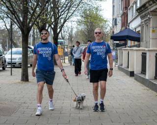 Two men in Terrence Higgins Trust t-shirts with a dog on a leash.