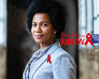 A smiling Black woman with a red ribbon pinned to her jacket overlaid with Terrence Higgins Trust logo and copy: 'More than a ribbon'.